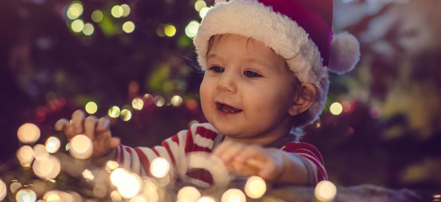 barnehagebarn med nisselue ved juletreet